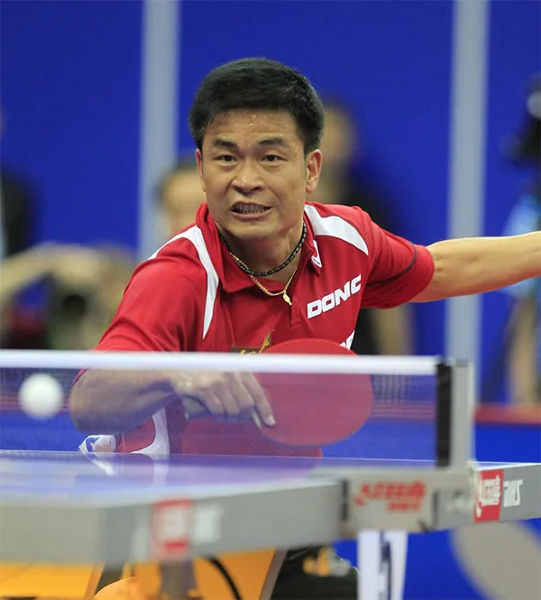 Defensive player Chen Weixing in a red Donic jersey chopping with long pimples rubber at an international table tennis match