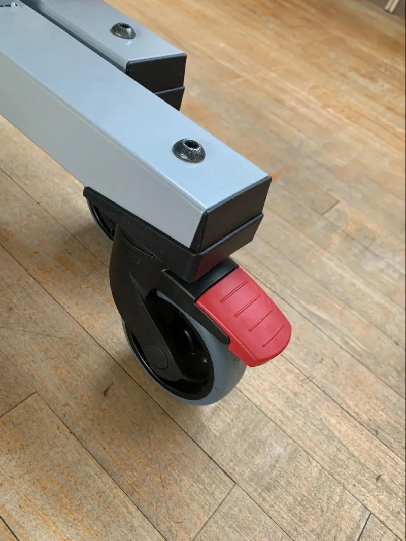Close-up of the locking caster wheel and red brake on the Donic Waldner Premium 30 table tennis table