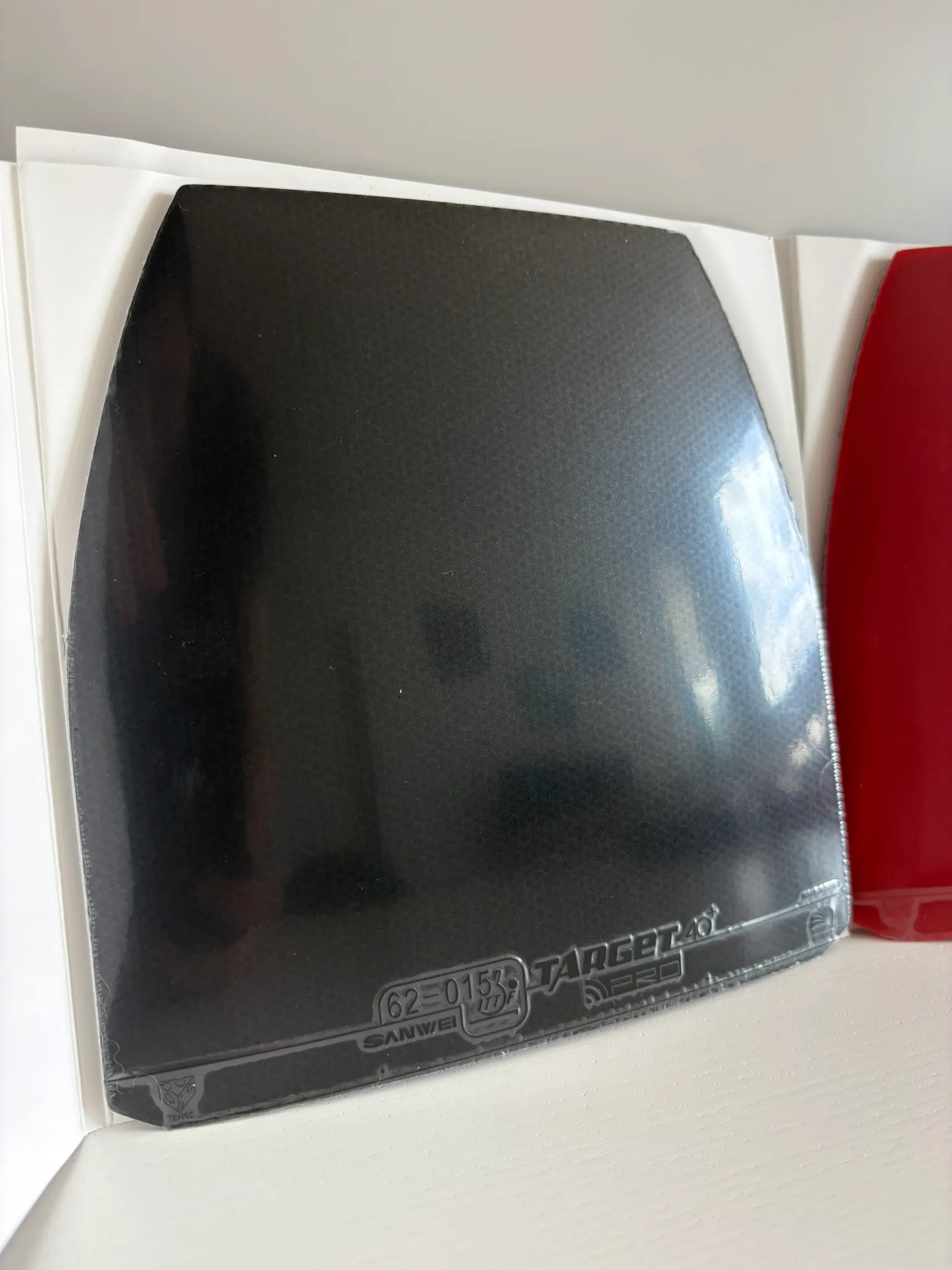 Close-up of the black Target Europe Soft topsheet in its plastic sleeve, showing a smooth matte surface.