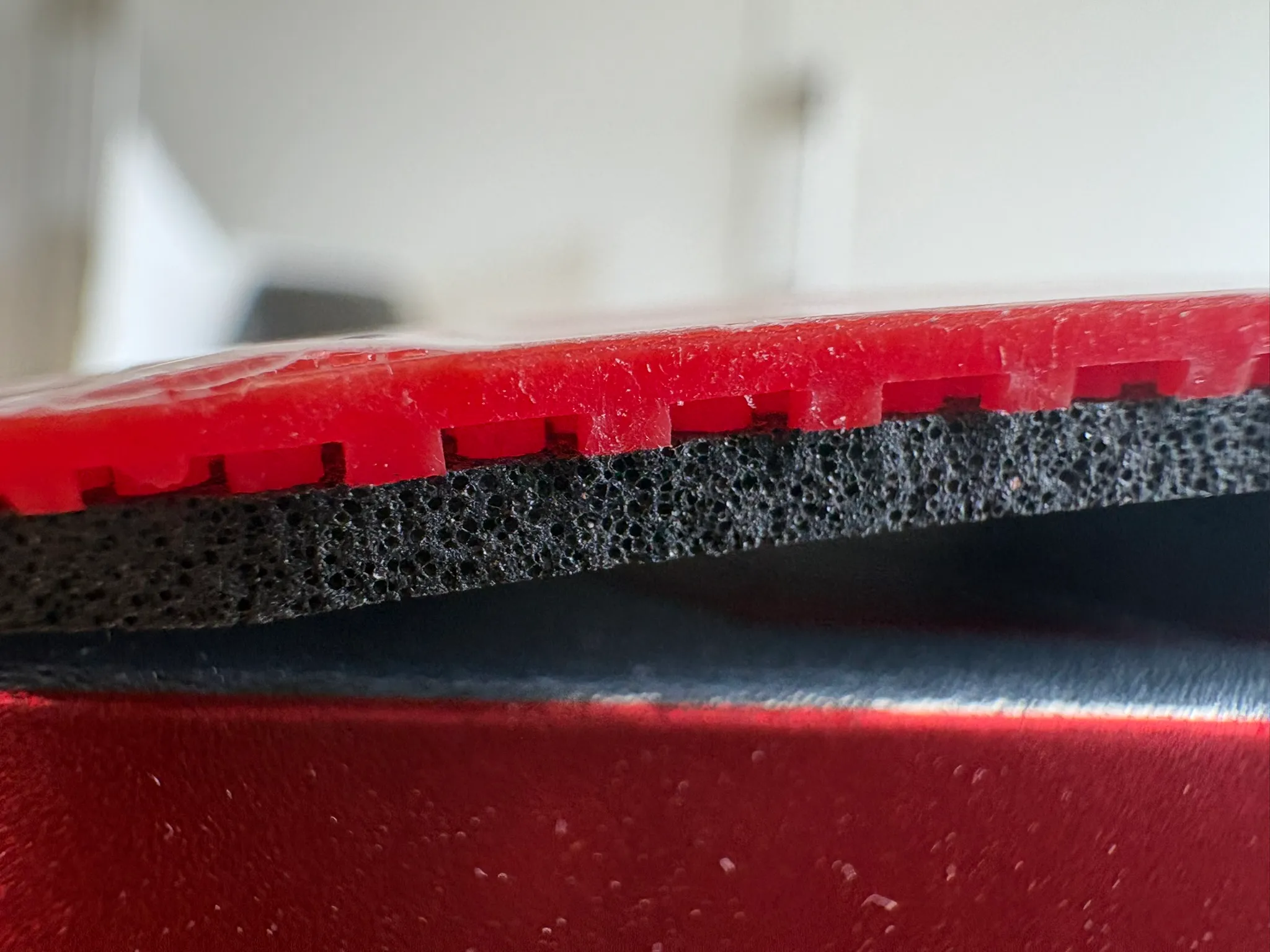 Side macro of the Target Europe Soft showing the red topsheet pips bending into the dark cake sponge.