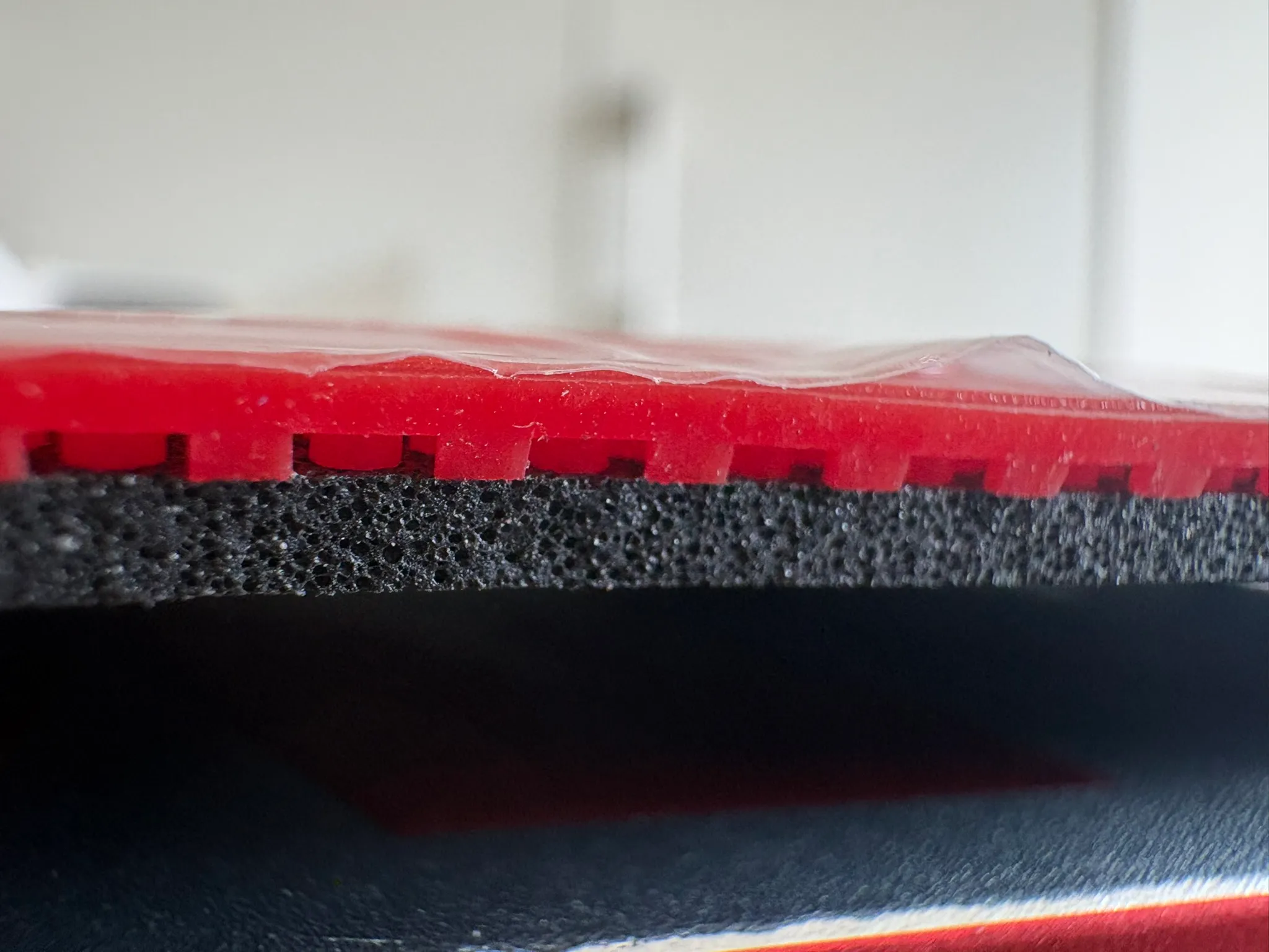 Macro view of the Target Europe Soft sponge edge, revealing large dark cake-style pores beneath the red topsheet pips.