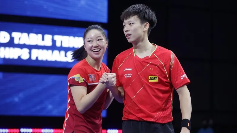 Two professional table tennis players in red national jerseys shaking hands at a World Table Tennis Championships final