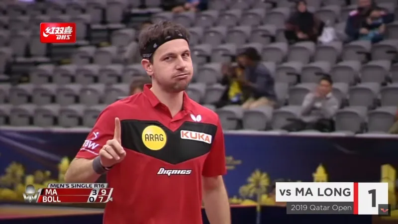 A picture of Timo Boll signaling he’s sorry after hitting a hand switch shot.