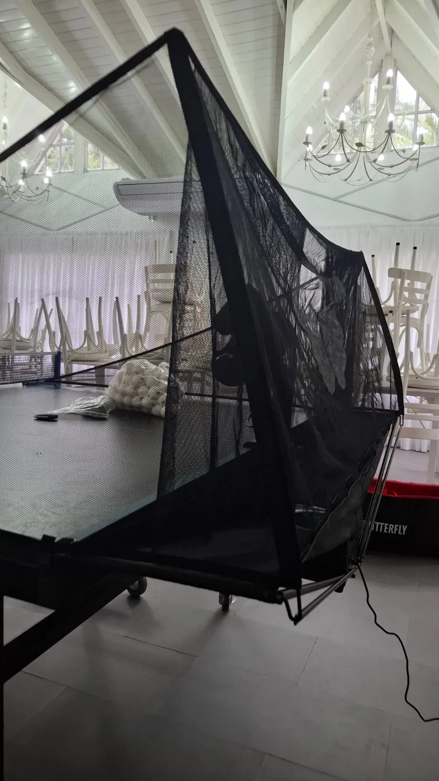 Butterfly Amicus Prime collection net deployed over a black table with a bag of white balls visible on the table surface.