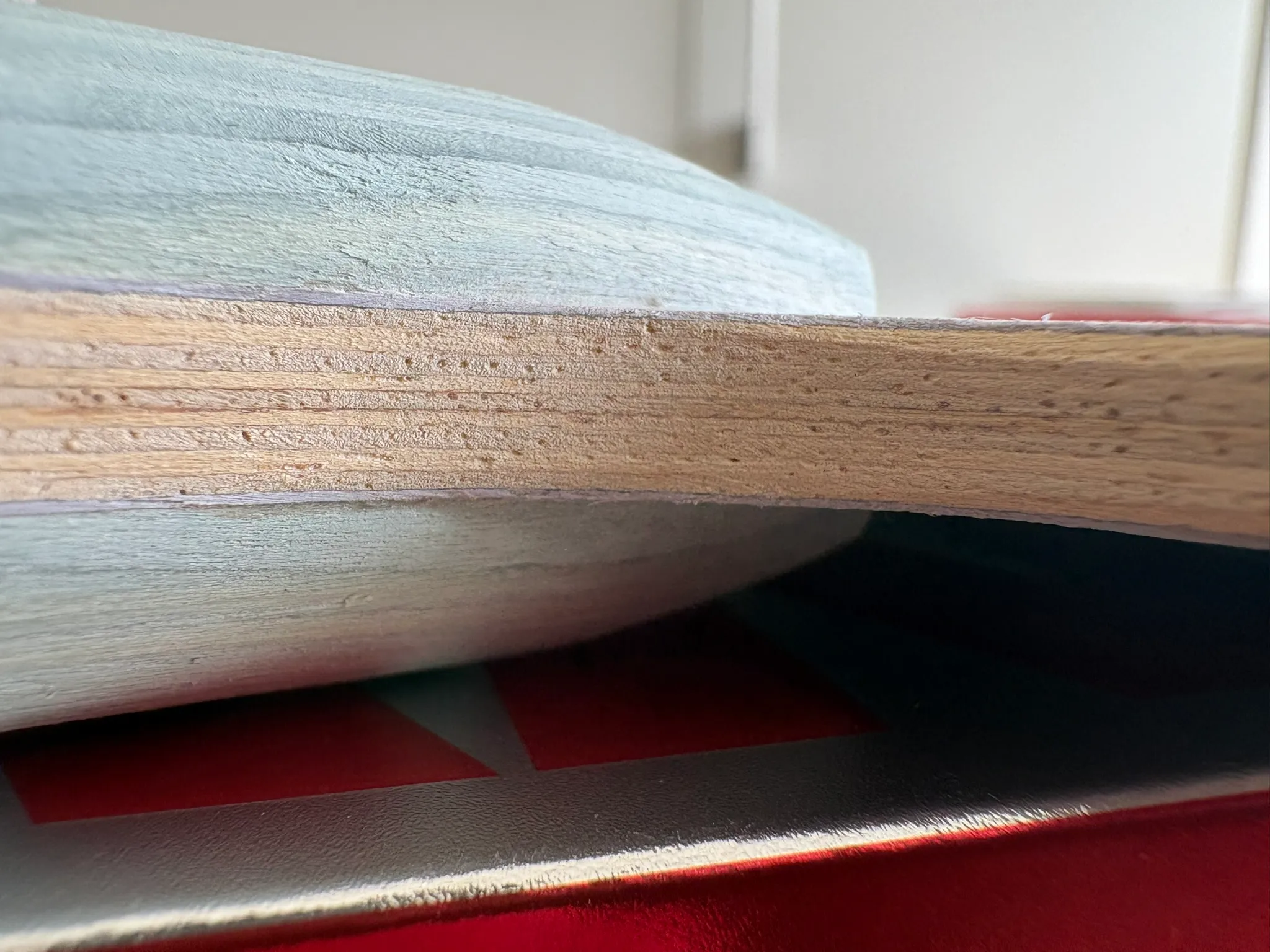 Extreme close-up of the blade edge showing many thin wood veneers layered with pale purple glue lines between them.