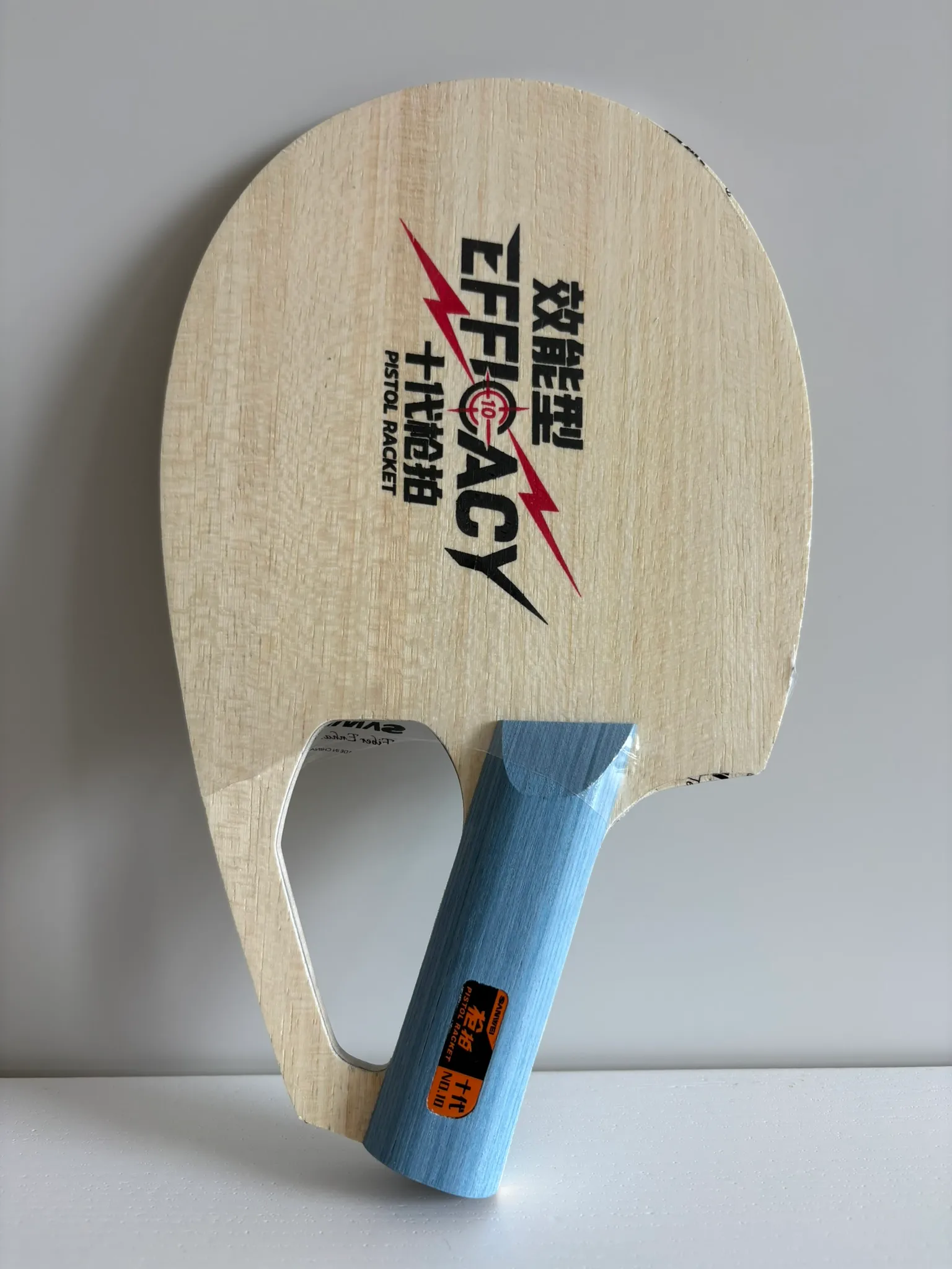 Bare Sanwei Pistol Racket standing upright with its blue diagonal handle and finger opening visible.