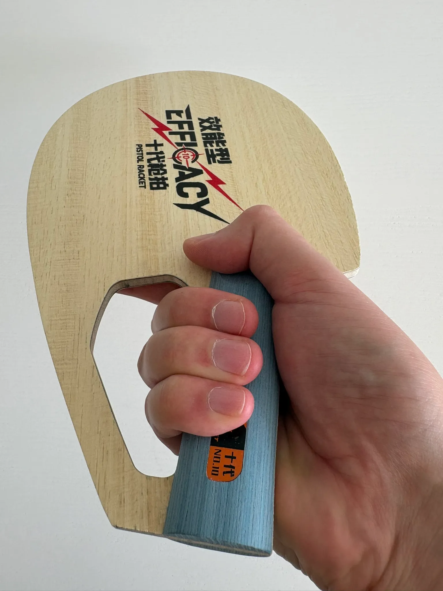 Right hand holding the Sanwei Pistol Racket with fingers wrapped through the handle opening.
