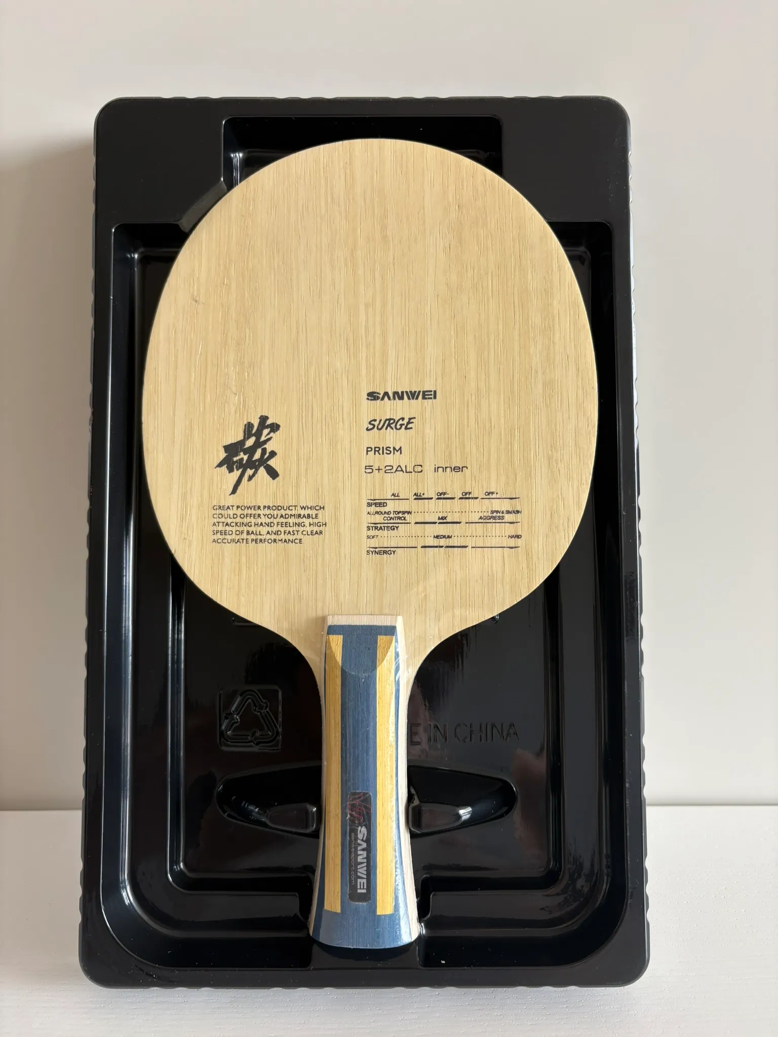 Sanwei Surge Prism blade seated in a black moulded blister tray, spec chart printed on the wood.